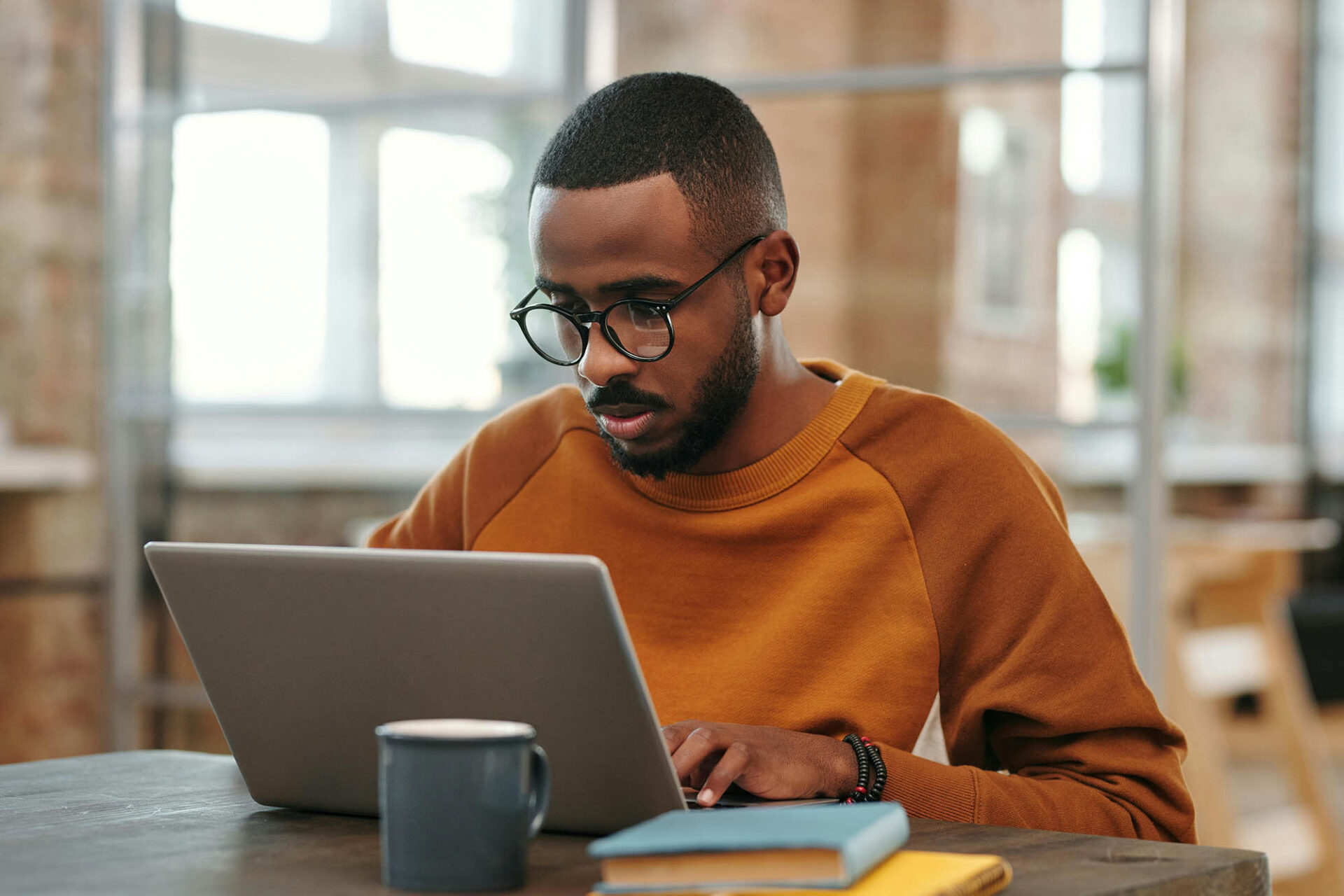 Finance professional focused on journal entry accounting tasks at laptop with coffee