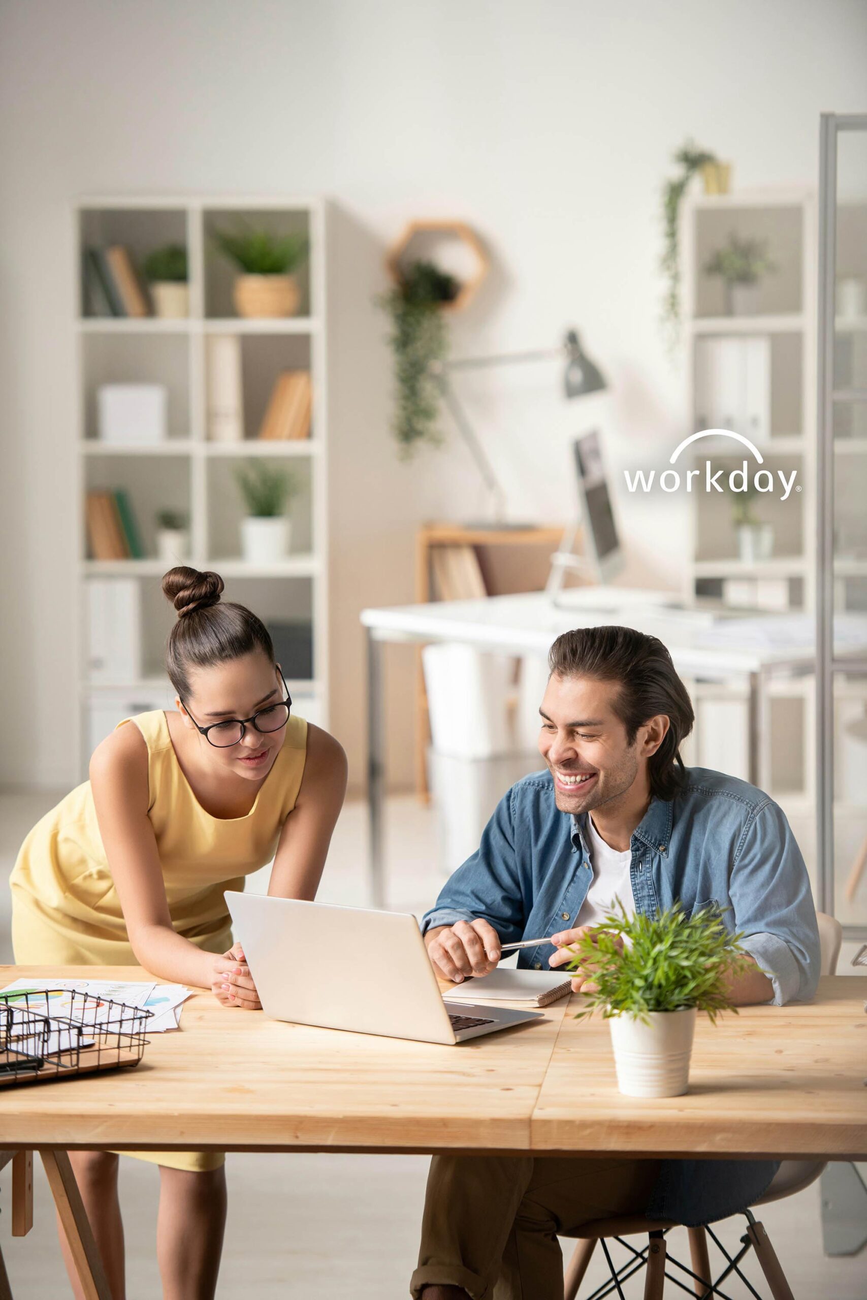 Industrial manufacturing team collaborating on laptop using financial reporting software with Workday system
