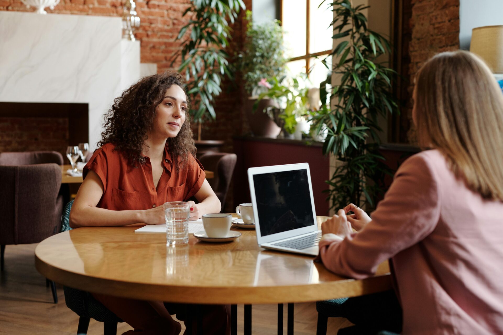 Two finance professionals having a strategic discussion over coffee, using a laptop to explore AI readiness and digital solutions for enhancing Office of Finance operations.
