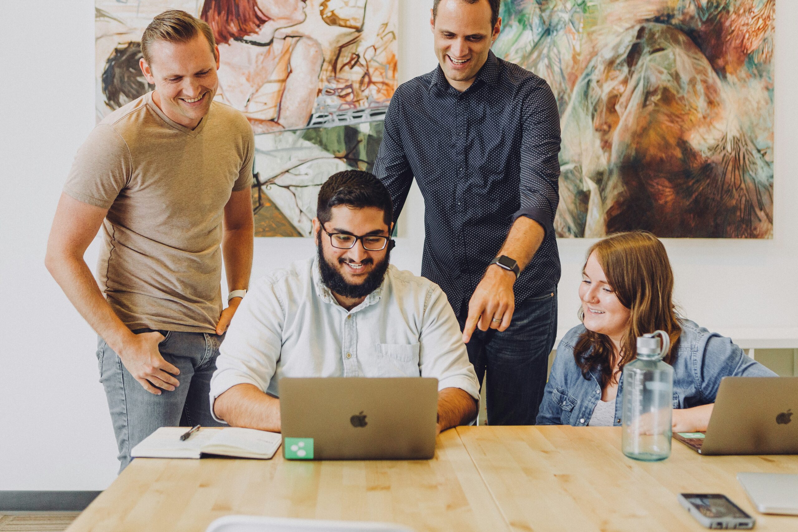 Three coworker gathered around a laptop discussing AI in the financial close